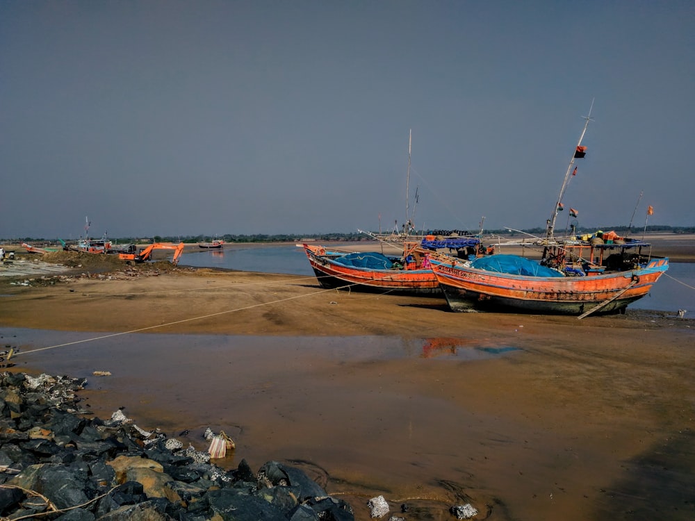 two orange boats under gray sky at daytime