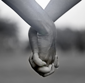 grayscale photo of two person holding hands