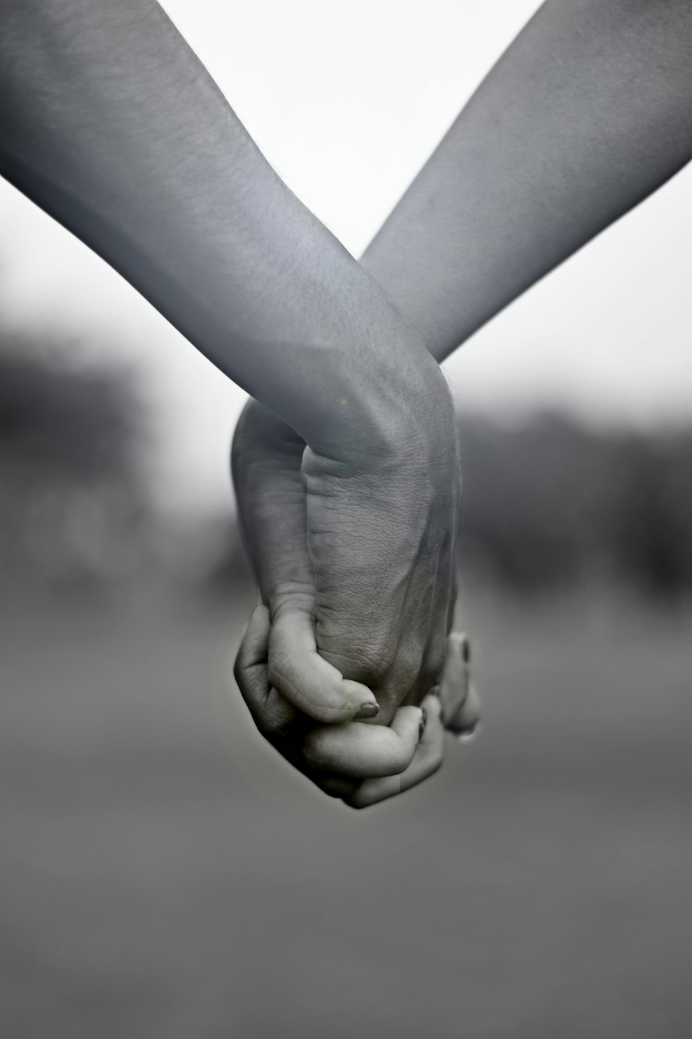 grayscale photo of two person holding hands