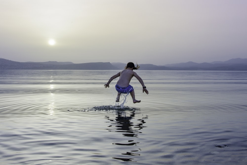 Fotografía de lapso de tiempo de niña saltando sobre el agua