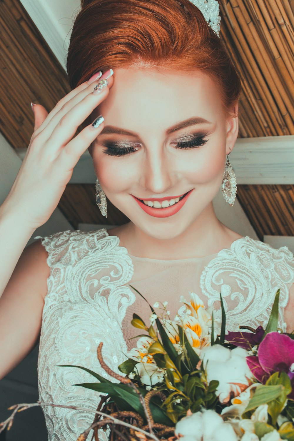 woman wearing bridal gown touching her forehead