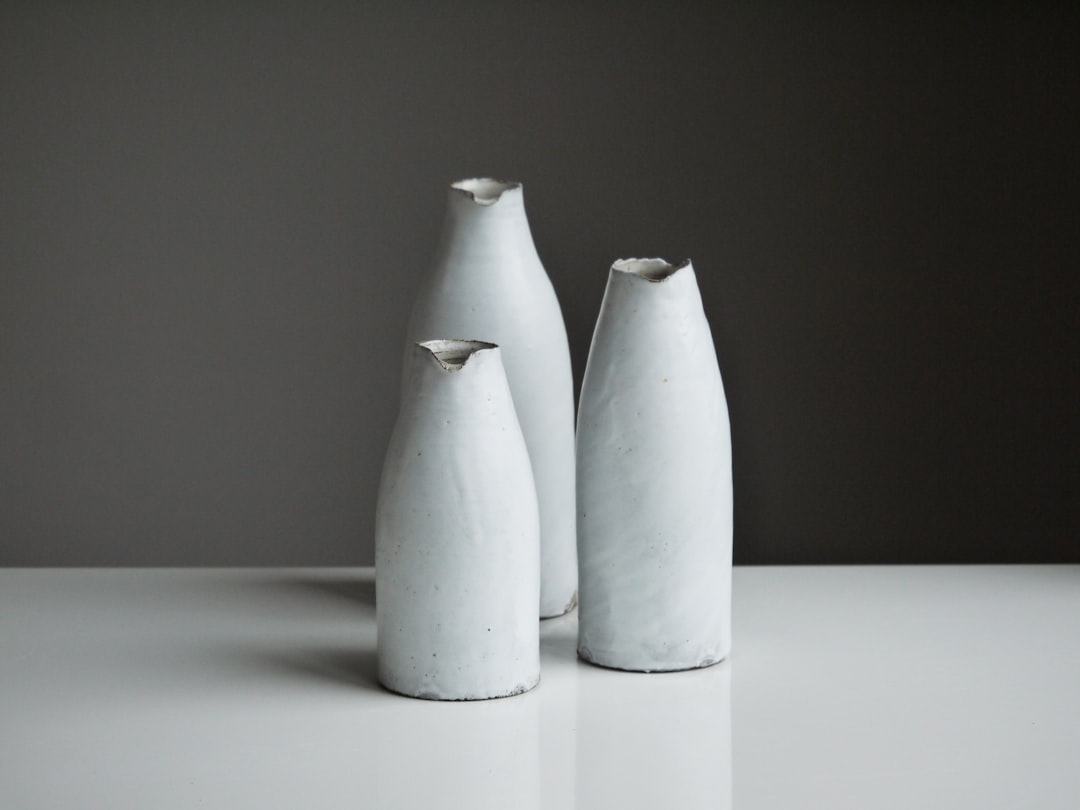 three white vases on table, Minimal. Full colour black and white.