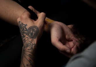 man's tattooing person's hand