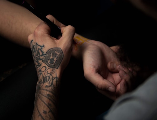 man's tattooing person's hand