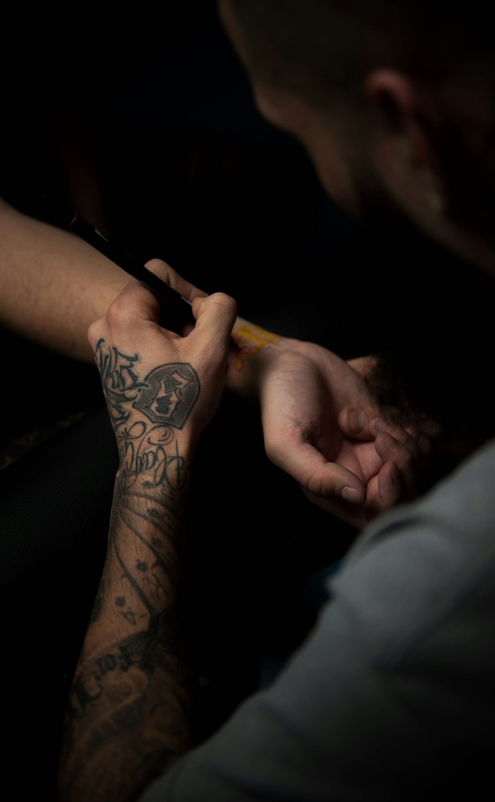 man's tattooing person's hand