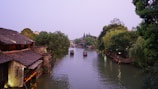 A serene boat gliding through the canals of Zhujiajiao ancient water town under soft morning light.