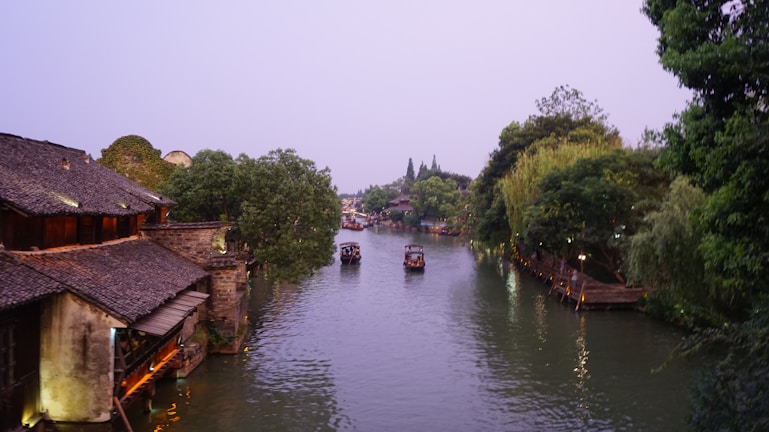 A serene boat gliding through the canals of Zhujiajiao ancient water town under soft morning light.