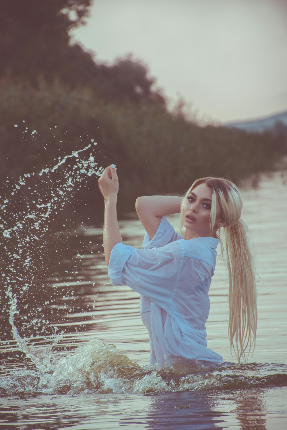 selective focus photo of woman on body of water holding her hair
