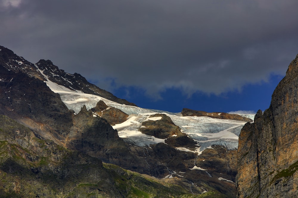 Montaña rocosa cubierta de nieve bajo un cielo nublado tenue