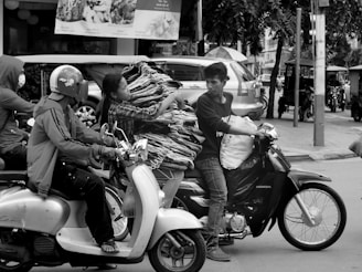 A professional motorbike taxi driver helping a passenger with luggage near a Paris train station.