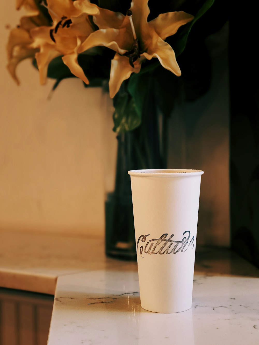 white plastic cup near orange flowers