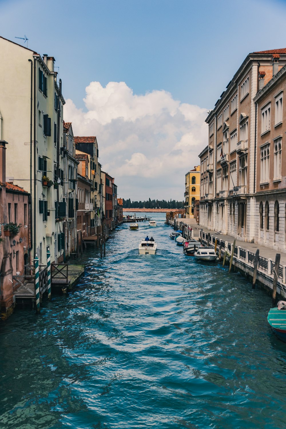 white boat in body of water in between white residential buildings