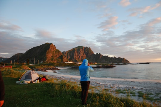 person in blue top standing beside body of water in Andenes Norway