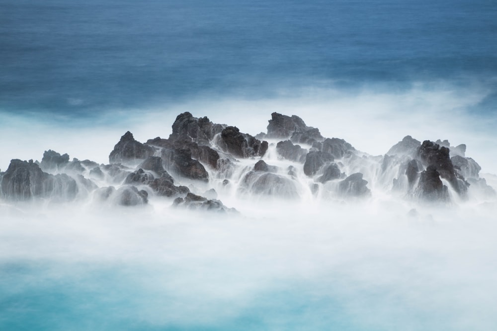 photo of sea waves hitting stones