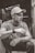 grayscale photo of man sitting on holding cigarette stick