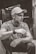 grayscale photo of man sitting on holding cigarette stick