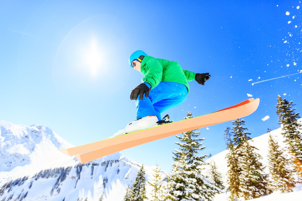 person wearing green jacket riding snow skis