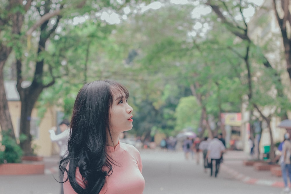 woman looking up near trees at daytime