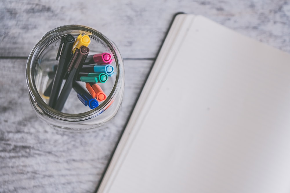 assorted-color markers in glass jar