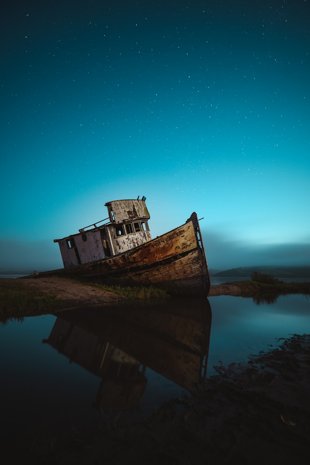 navio abandonado na costa sob o céu com estrelas