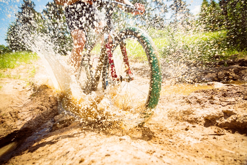 person riding bike on puddle with water splashing during daytime