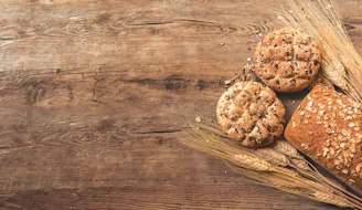 Close-up of fresh natural grains and artisanal products arranged on rustic wooden table.