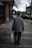 man walking using brown cane carrying white bag near brown buildings at daytime