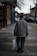 man walking using brown cane carrying white bag near brown buildings at daytime
