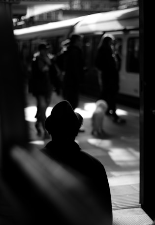 grayscale photo of person standing on train station