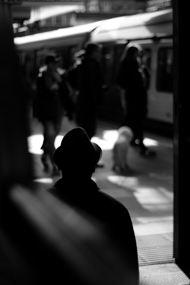 grayscale photo of person standing on train station