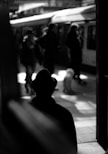 grayscale photo of person standing on train station