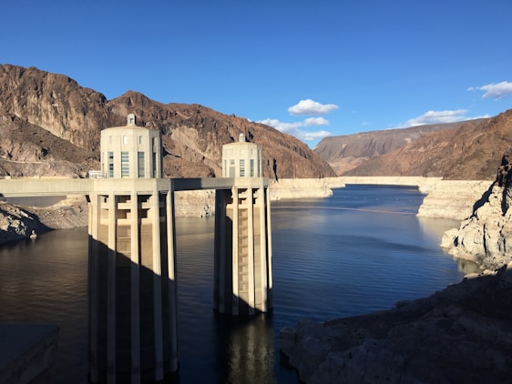 A professional engineer reviewing dam design blueprints on site with a backdrop of a water reservoir.