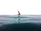 Woman sitting on a surfboard in calm water, looking towards the horizon with a peaceful expression.