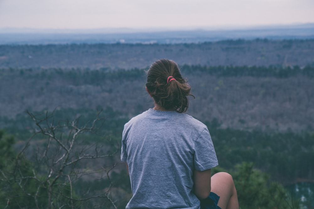 sitting woman looking at the trees during daytime