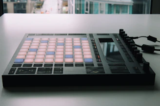 Close-up of a sleek MIDI controller glowing purple in a dark studio.