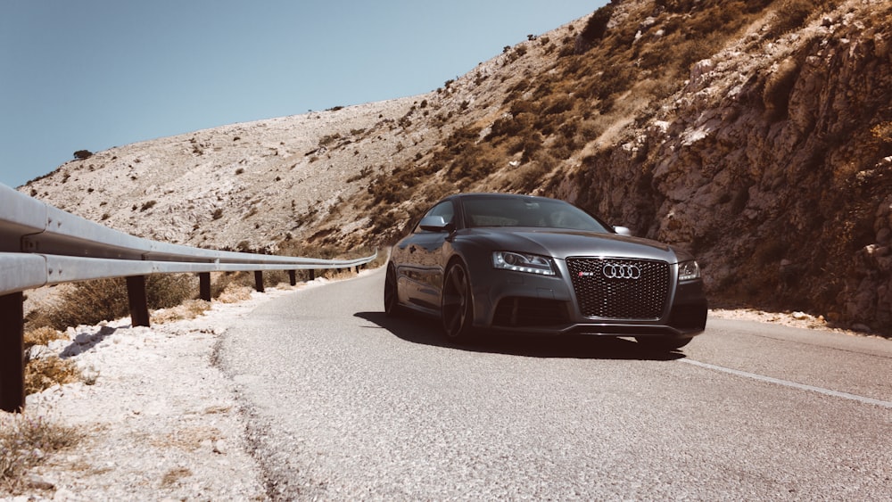 black Audi car passes on asphalt road