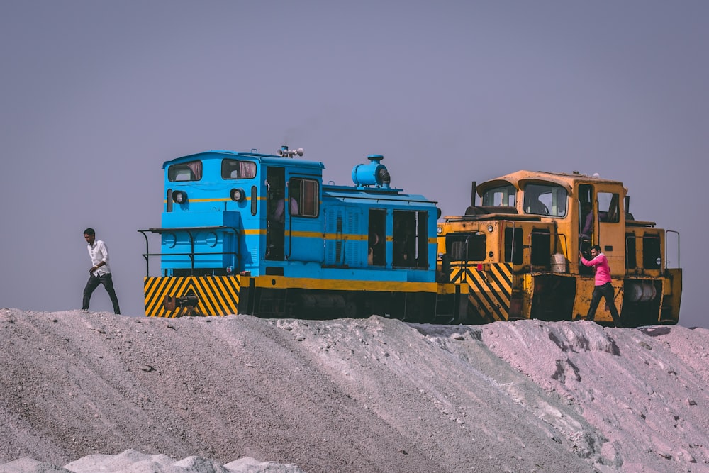 man walking in front of yellow and blue train