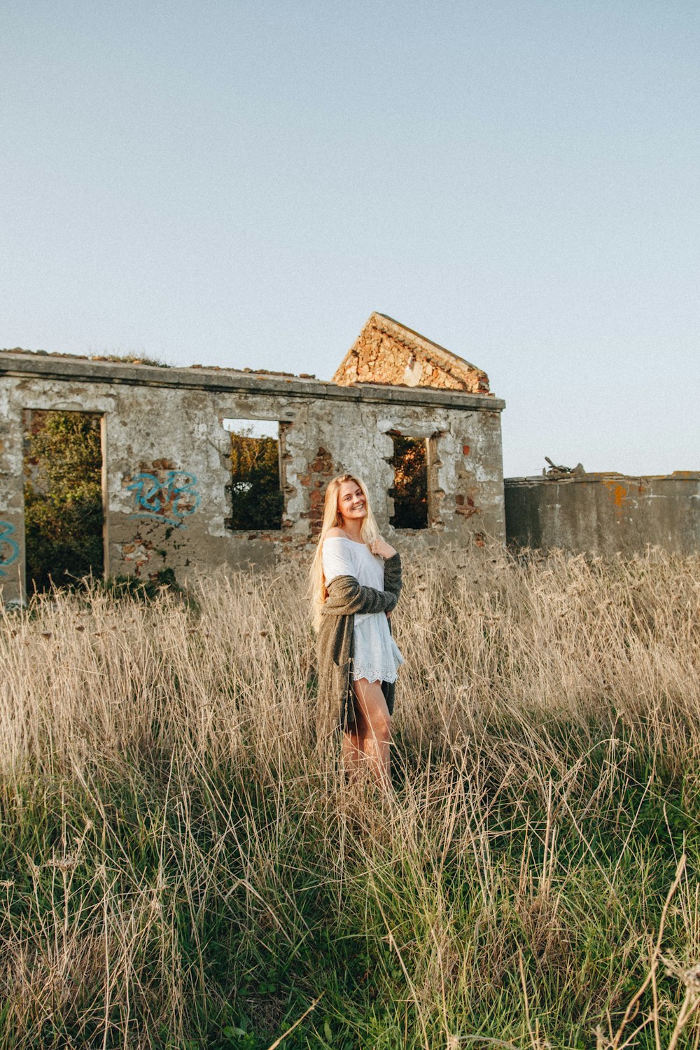 woman wearing white dress standing and surrounded by brown grasses