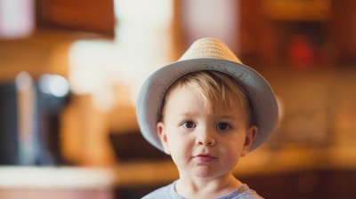 closeup photo of boy wearing brown fedora hat
