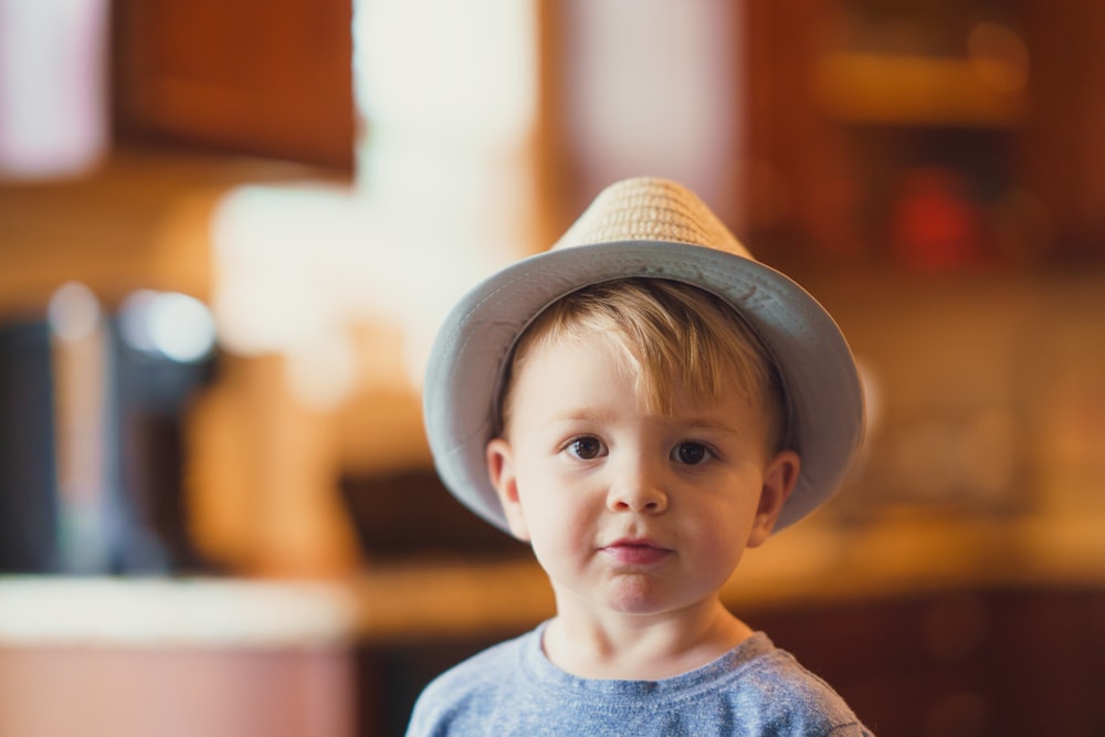 closeup photo of boy wearing brown fedora hat