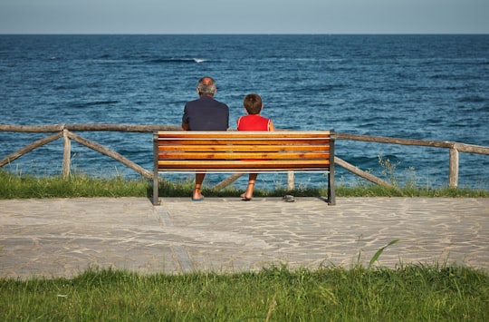 two person sitting on bench beside body of water in Dorgali Italy