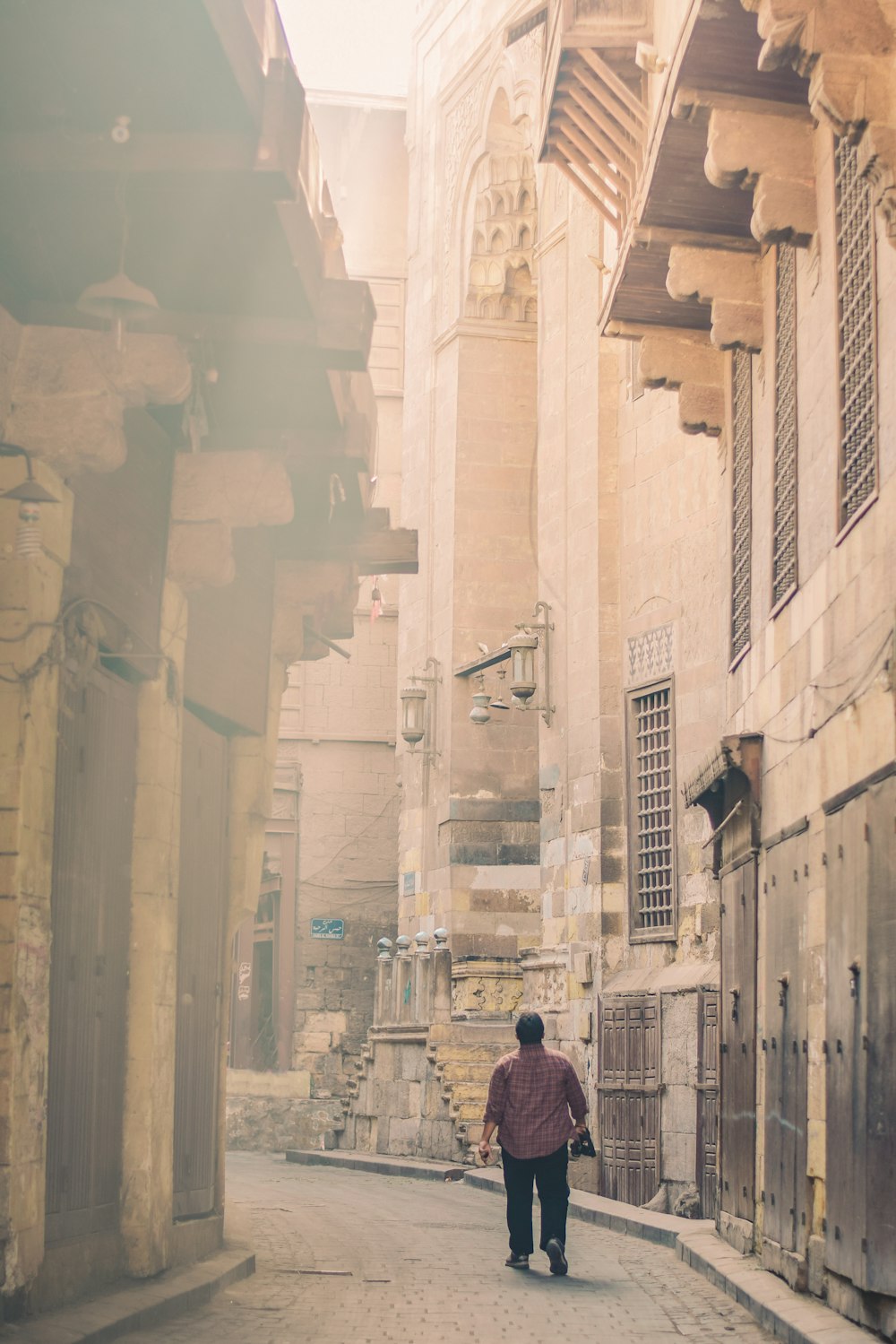 man walking between concrete buildings at daytime