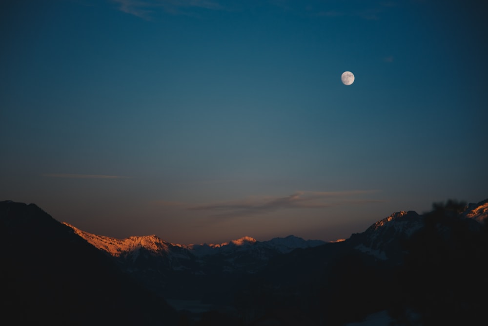 snow-capped mountain at night time with moon