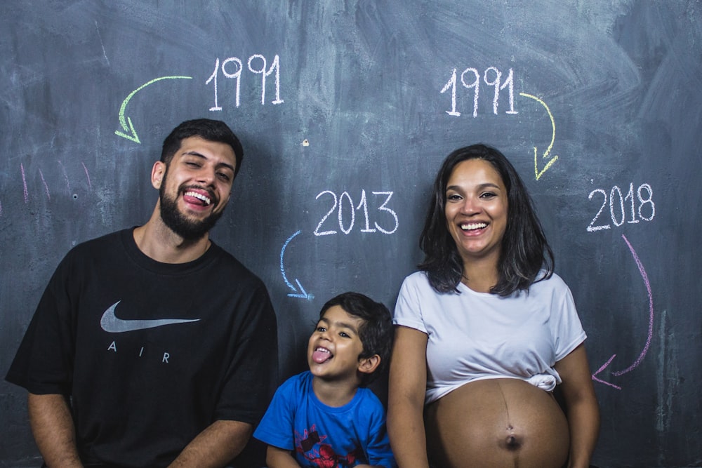 man, boy, and girl standing under chalkboard