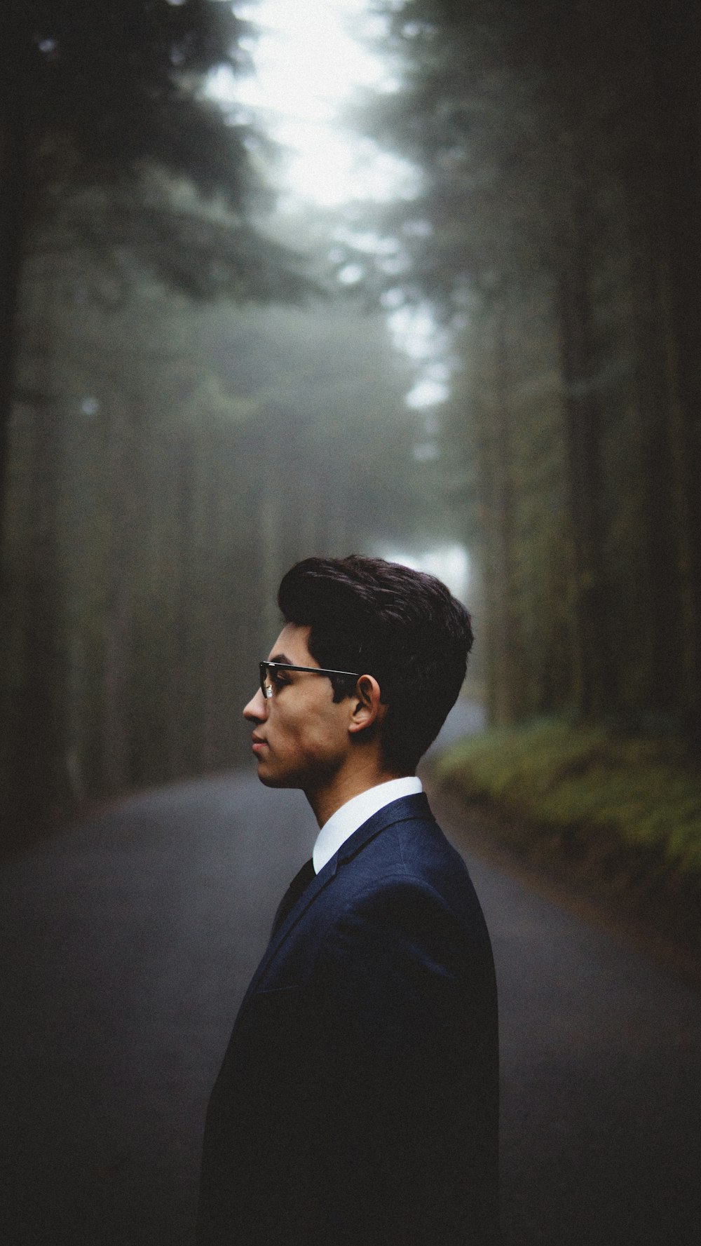 man standing in woods near road during daytime