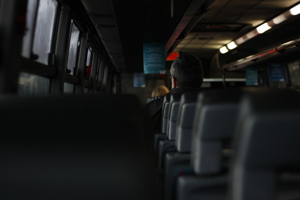 um homem sentado em um ônibus olhando pela janela