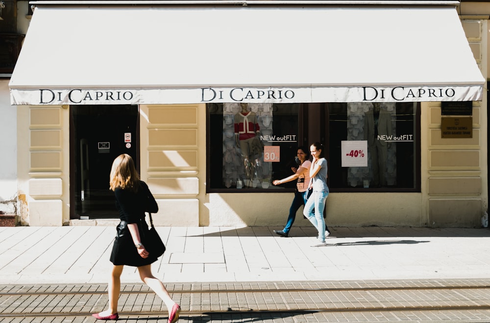 três mulheres caminhando em frente à fachada da loja Di Cario