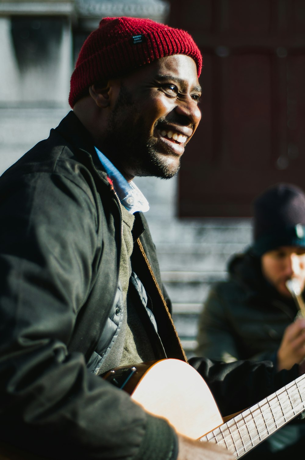 man holding guitar near man playing flute