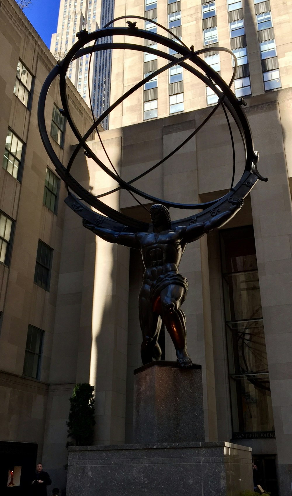 昼間、建物の近くで地球儀の像を持つ男