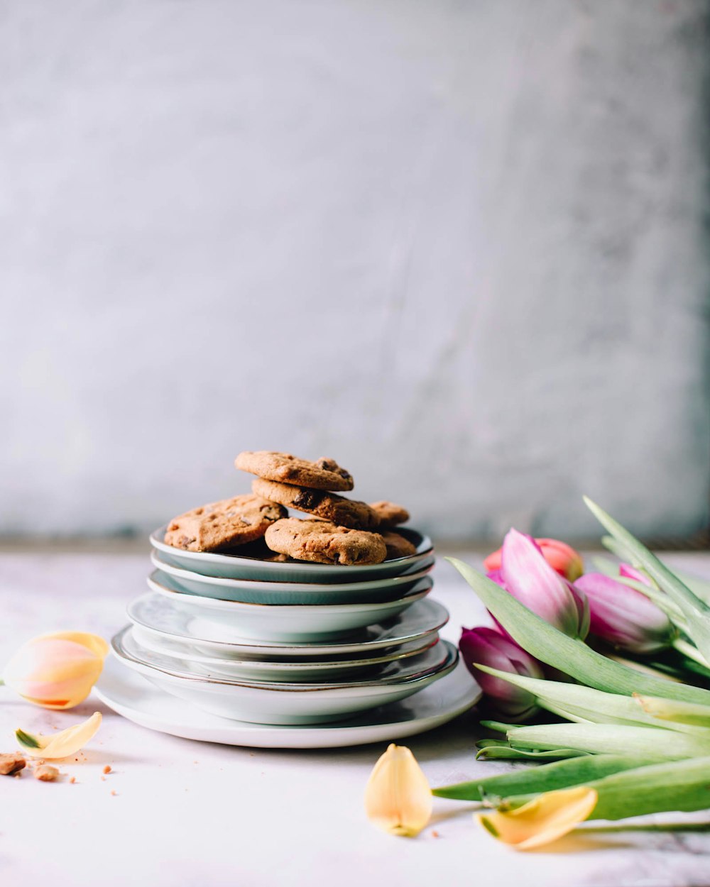 cookies on round white ceramic saucers beside pink tulips flowers